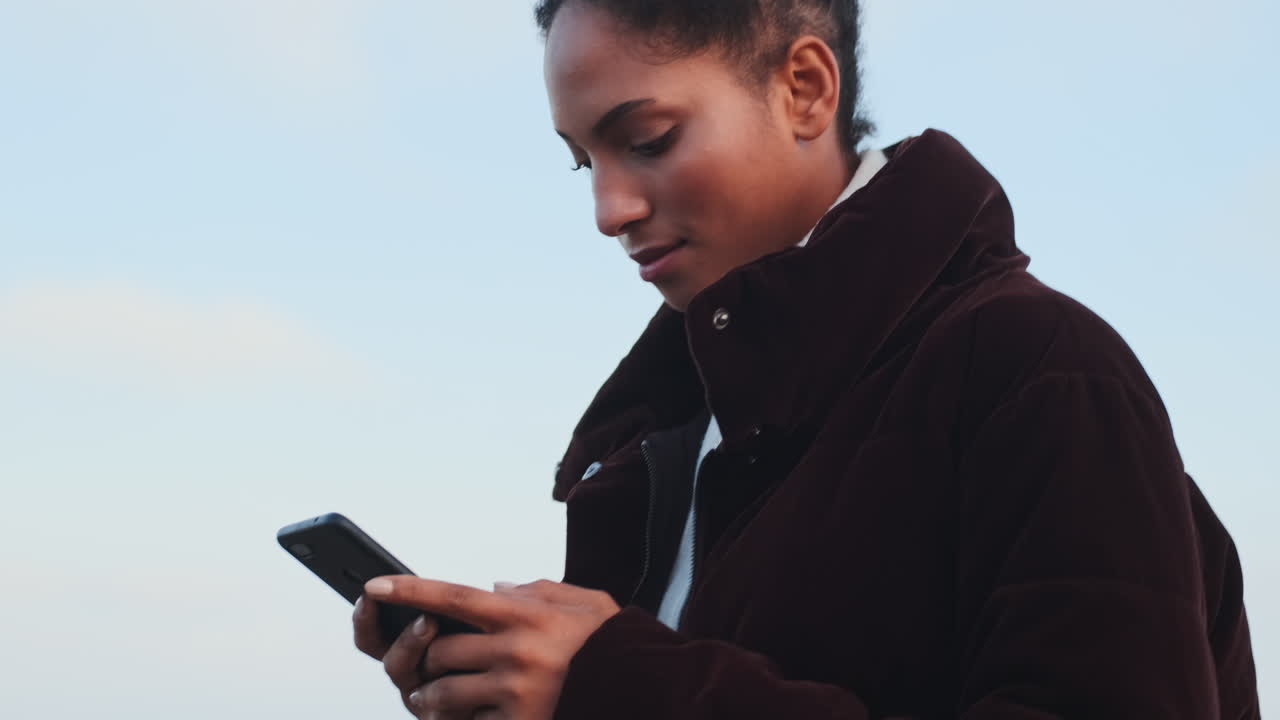 una chica afroamericana usando un teléfono móvil.