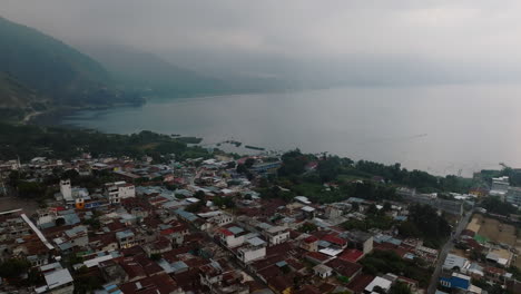 aerial: lakeside view of san juan la laguna village in guatemala during a cloudy day