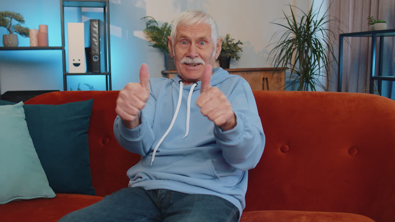 un anciano abuelo feliz mirando con aprobación a la cámara mostrando los pulgares hacia arriba, como un signo positivo