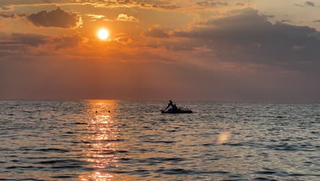 Schöner-Goldener-Sonnenuntergang-Und-Silhouette-Von-Menschen-Auf-Dem-Tretboot-Und-Schwimmen-Im-Sonnenmeerweg