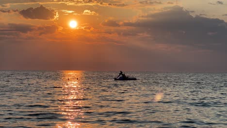 beautiful golden sunset and silhouette of people on pedal boat and swimming in the sun sea path