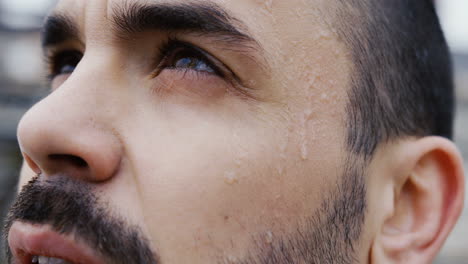 close-up view of caucasian bearded man looking the sky with drops of sweat on his face and then looks at the camera