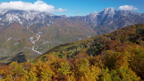 panoramic cinematic shot of autumn scene with yellow-red trees and mountains in sunlight