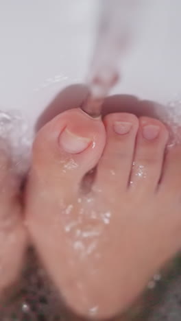 woman feet under hot running water bathing at home. lady rests taking foamy bath in comfortable bathroom closeup. recreation and enjoyment routine