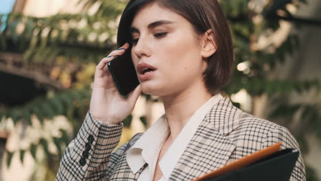 una mujer elegante haciendo una llamada de negocios al aire libre.