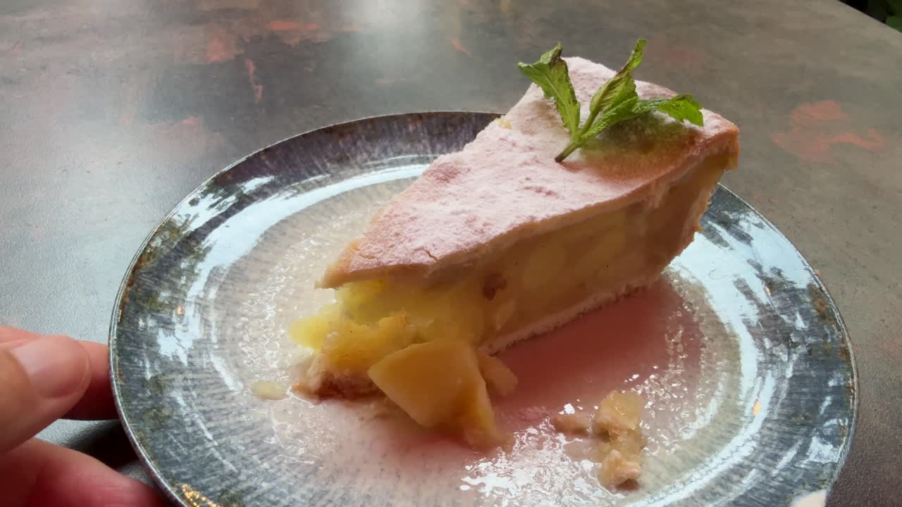 Close up of a delicious apple pie on a blue ceramic plate. Personal perspective eating with fork
