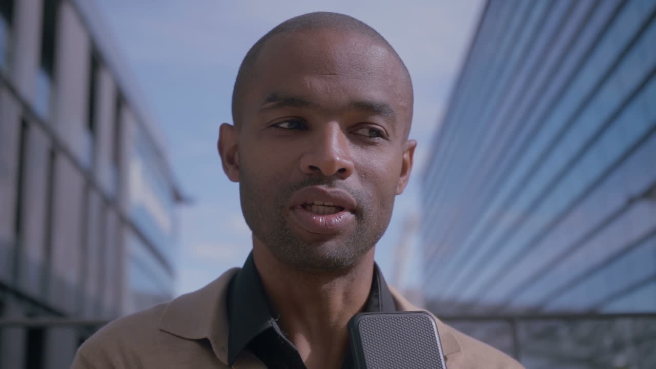 hombre afroamericano positivo teniendo una conferencia de audio en un teléfono inteligente