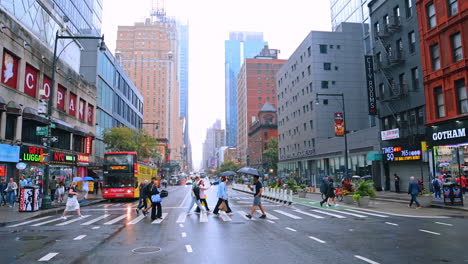 Pedestrians cross the road in New York on rainy day. Low angle view on the high-rise buildings of metropolis