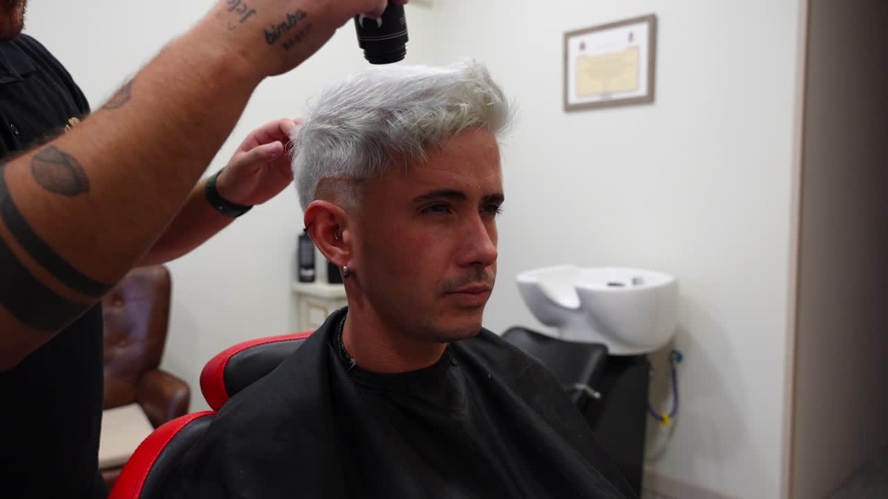 Hairdresser adds texture powder to client’s hair for finishing touch in barbershop