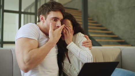 una pareja joven viendo una película de terror en la computadora portátil.