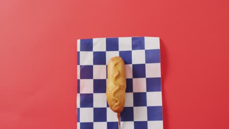 video of corn dog with mustard on a red surface