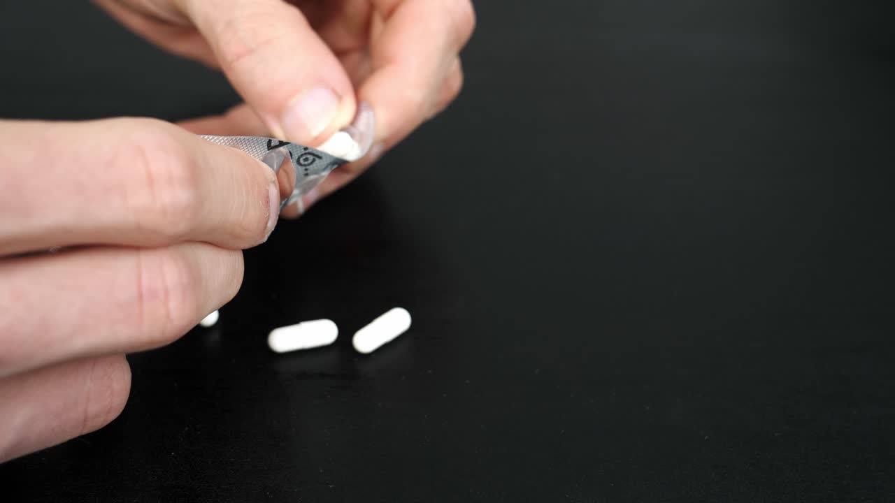 플라스틱 패키지에서 테이블로 약을 밀어내는 남자