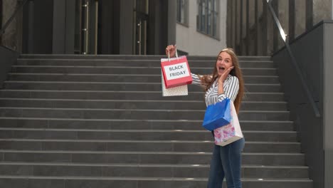 girl showing black friday inscription on shopping bags, smiling, satisfied with low prices purchases