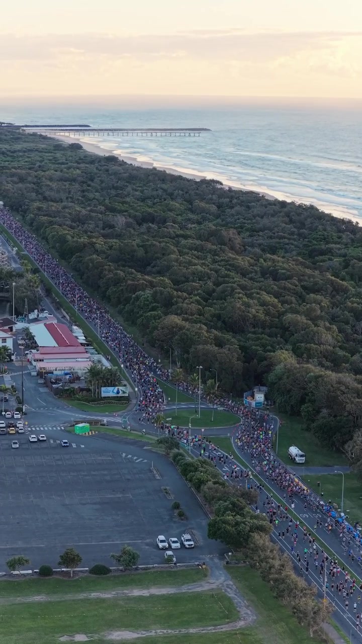 Riprese aeree verticali con carrello in avanti sopra il percorso della Maratona della Gold Coast a Southport, con la costa e Surfers Paradise, Queensland, Australia.