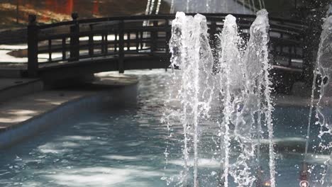 water fountain in a park with a bridge