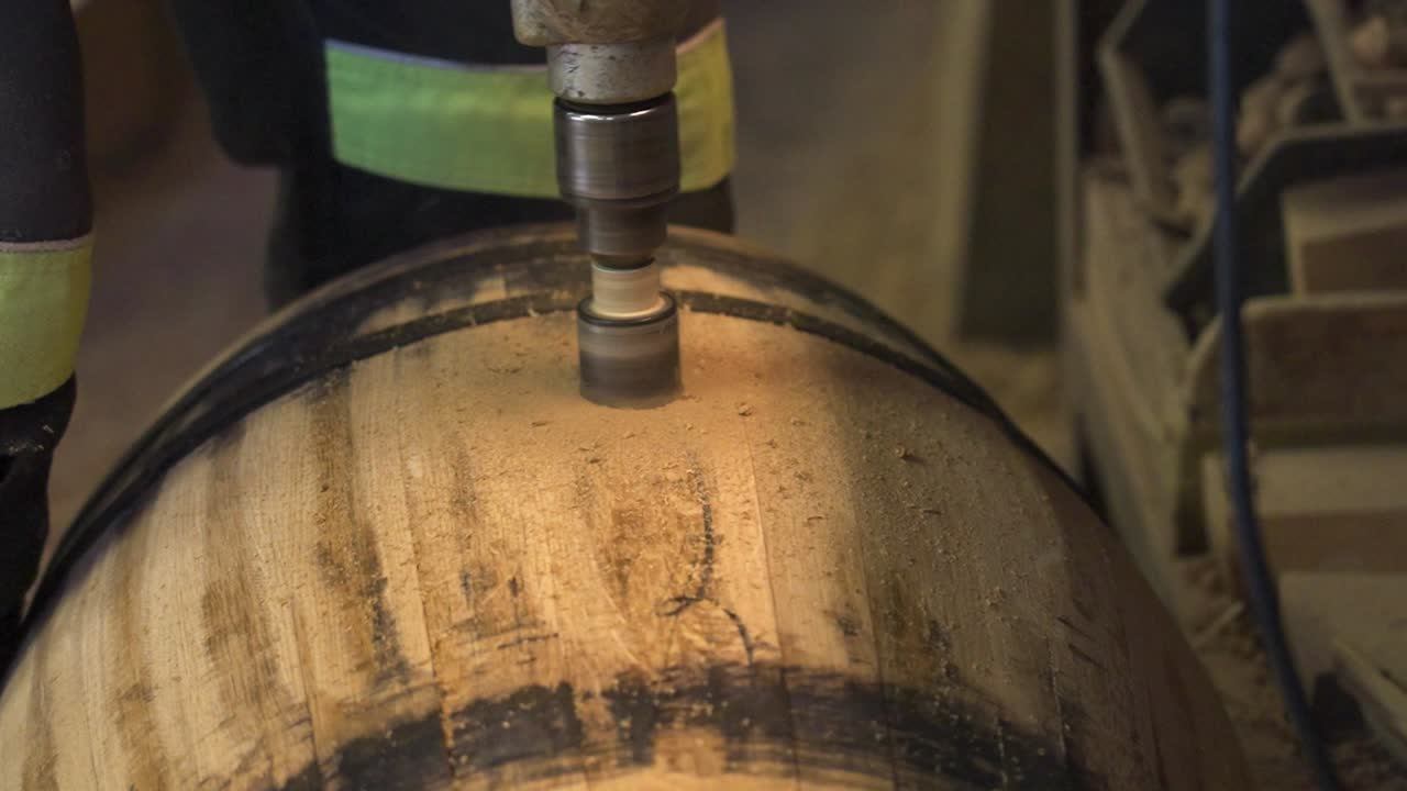 drilling a hole into a wooden barrel in an old workshop