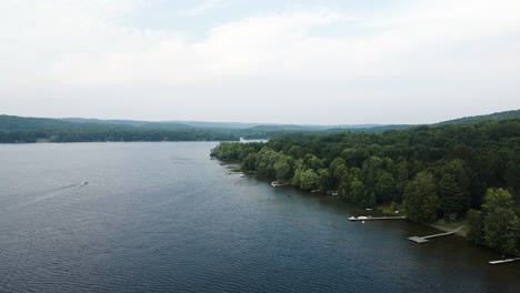 private docks reach out into lake out from trees, aerial wide angle perspective