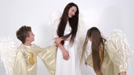 mom with children daughter and son dressed in angel costumes they dance on a white background mom with children daughter and son dressed in angel costumes they dance on a white background in the studio