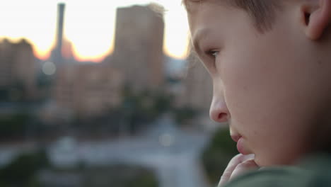 boy with sad look staring at the city from the balcony