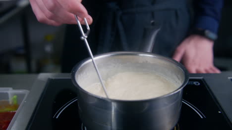 chef cook mixing cream sauce by spiral whisk