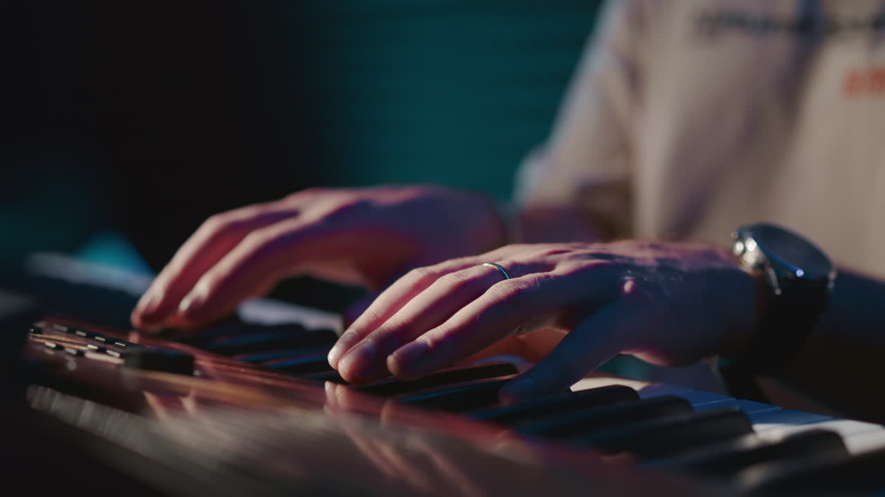 작곡가는 음악 스튜디오 클로즈업에서 신디사이저를 연주합니다. 전문 음악가는 레코드 센터에서 디지털 악기로 멜로디를 작성합니다.