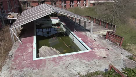 imágenes aéreas de drones orbitando a la derecha alrededor de una piscina cubierta abandonada y un hotel