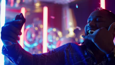 African-american-man-using-smartphone-at-party.-Afro-guy-making-selfie-in-club