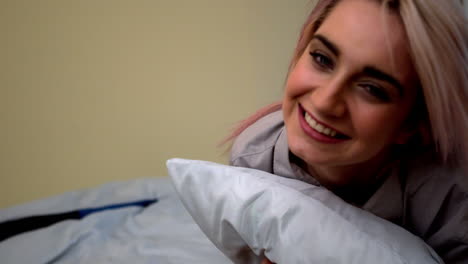 una joven rubia y bonita rodando en su cama.