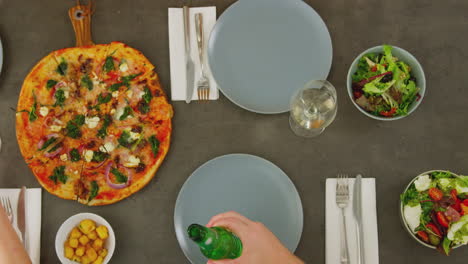 Overhead-View-Of-Friends-Making-Toast-Before-Eating-Pizza-In-Restaurant-Together