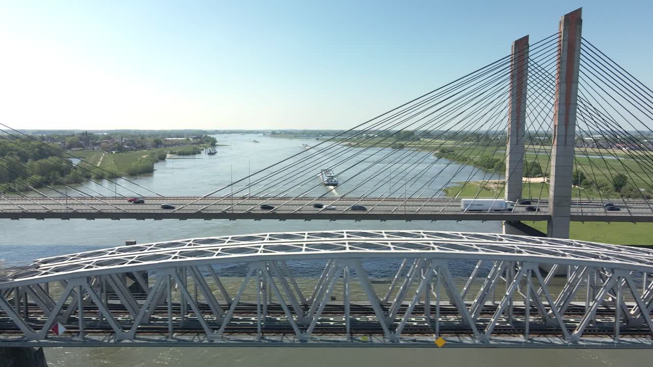 volando en paralelo al puente de la autopista y al puente del ferrocarril con un barco cruzando el río al fondo en un día claro y soleado