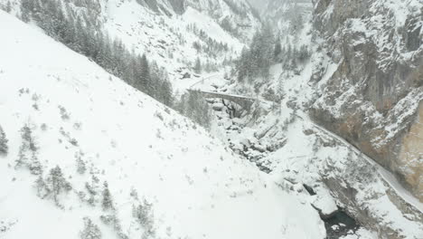 luftaufnahme einer steinbrücke über einen kleinen fluss in einer schneebedeckten landschaft