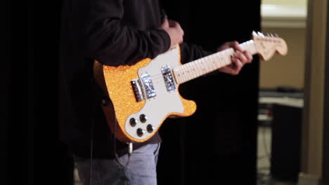 Primer-Plano-De-Un-Guitarrista-Tocando-Un-Concierto-Con-Una-Guitarra-Dorada-Brillante