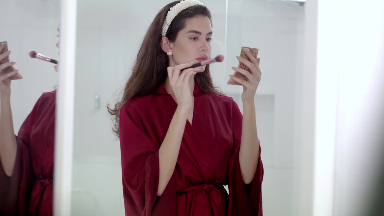 Young attractive woman makes use of small compact make-up and brush set