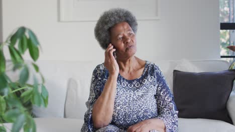 African-american-senior-woman-sitting-on-the-couch-and-using-smartphone