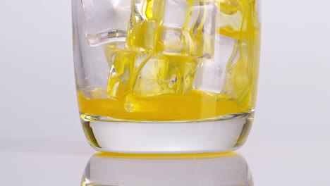 orange juice pouring into a glass with ice