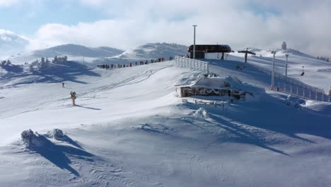 people ski down slope from ski lift in snowy jahorina, drone parallax