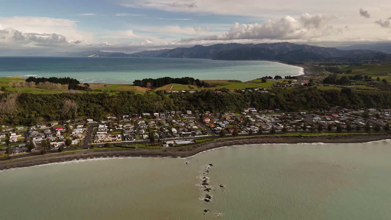 Kaikoura coastal town, dark beach, green hills, New Zealand. Aerial drone panoramic view