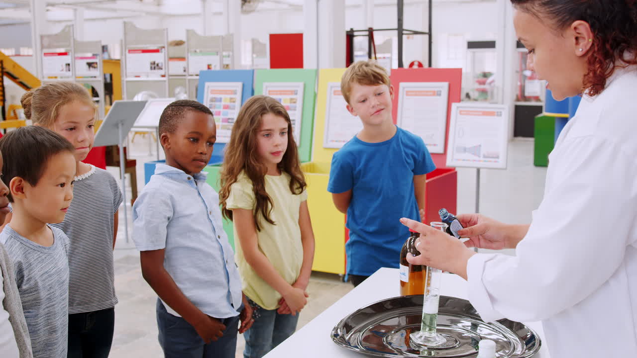 niños de la escuela viendo un experimento en un centro de ciencia