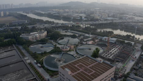 Aerial-view-of-water-treatment-plant-near-a-highway-with-dense-traffic-on-the-sunset-in-Guangzhou,-China