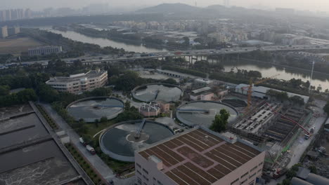 Vista-Aérea-De-La-Planta-De-Tratamiento-De-Agua-Cerca-De-Una-Carretera-Con-Tráfico-Denso-Al-Atardecer-En-Guangzhou,-China