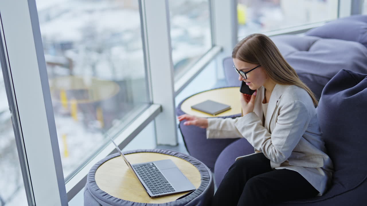 Businesswoman working on laptop and having a phone call in a modern office