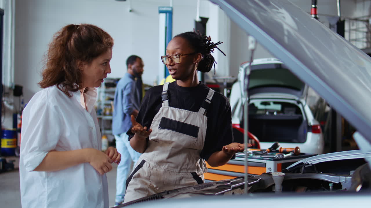 Repairman in garage fixes customers car