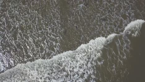 Aerial-birds-eye-view-following-a-wave-in-the-sea