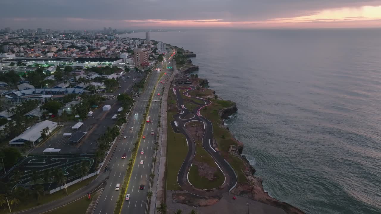 Autostrada Santo Domingo, ripresa aerea notturna in avanti con luci del traffico, skyline