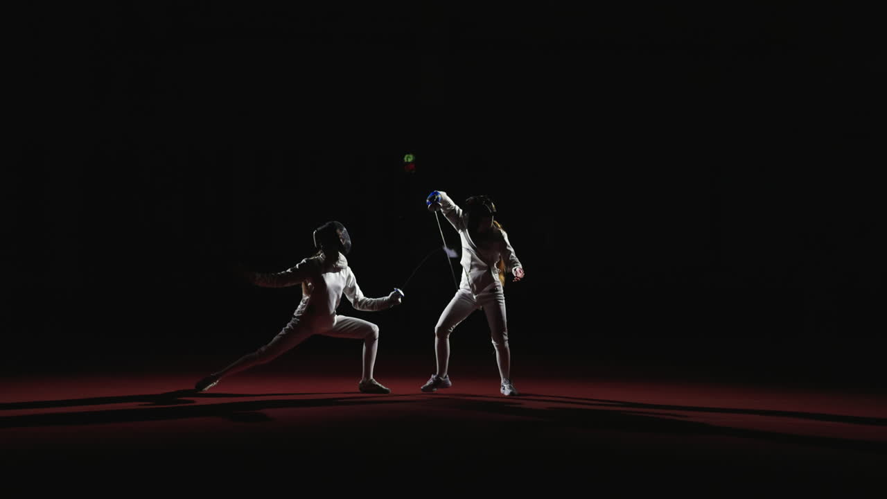 Two female fencers compete in a fencing match