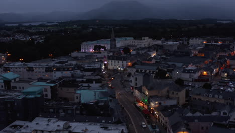 Aerial-footage-of-town-centre-with-church-and-luxury-hotel-at-dusk.-Backwards-reveal-of-buildings-along-illuminated-street.-Killarney,-Ireland