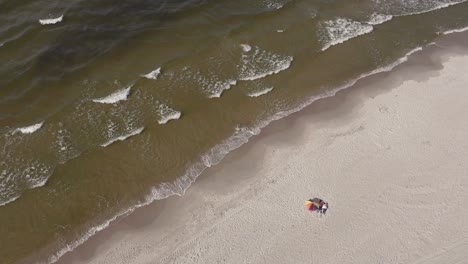 people under parasol relaxing at the beach by the baltic sea