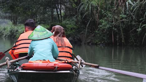 two people rowing a boat in a lush river setting