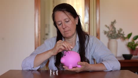 a woman is putting coins into the piggy bank - close up