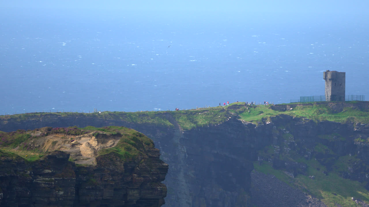 Perched on the Cliffs of Moher, a distant tower watches over the Atlantic. The sheer cliffs and endless ocean stretch beyond, showcasing Ireland’s rugged and timeless coastal beauty.